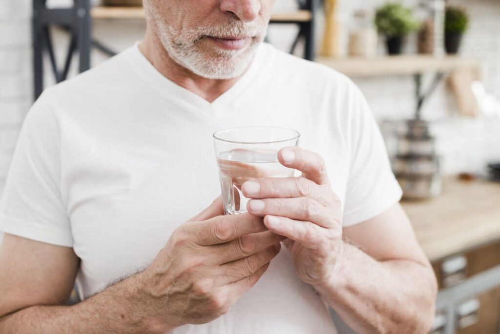 senior buvant un verre d'eau pour lutter contre la déshydratation