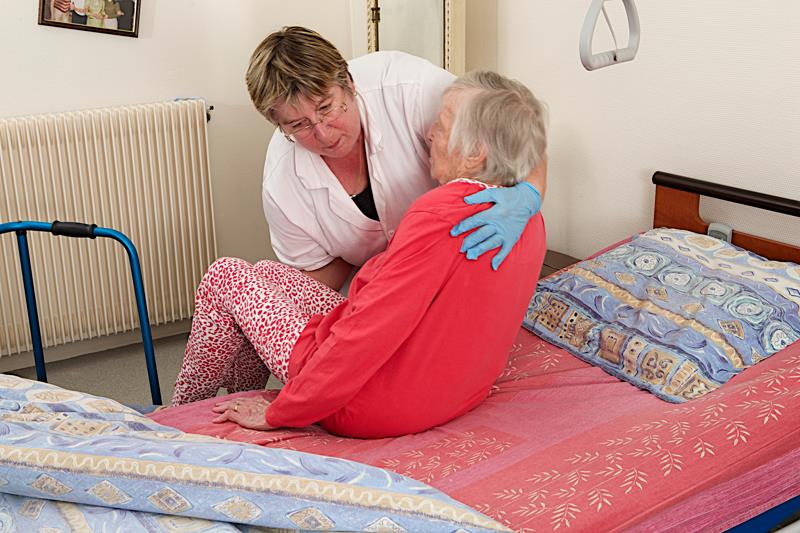Aide à domicile assistant une personne âgée au couchage