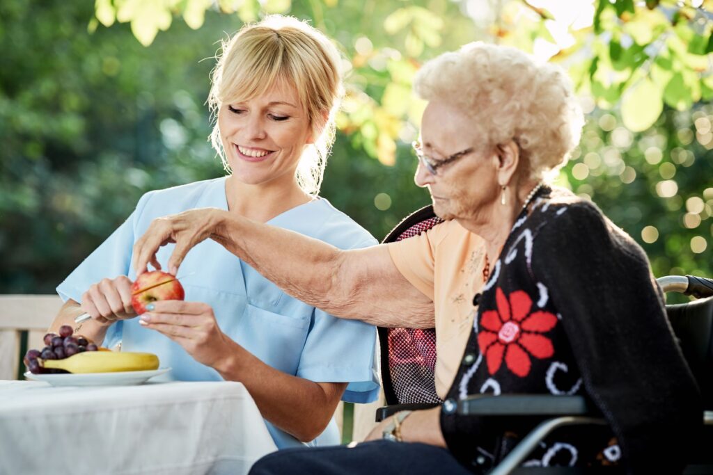 Repas d'une personne âgée avec une aide soignante dans le jardin de l'EHPAD