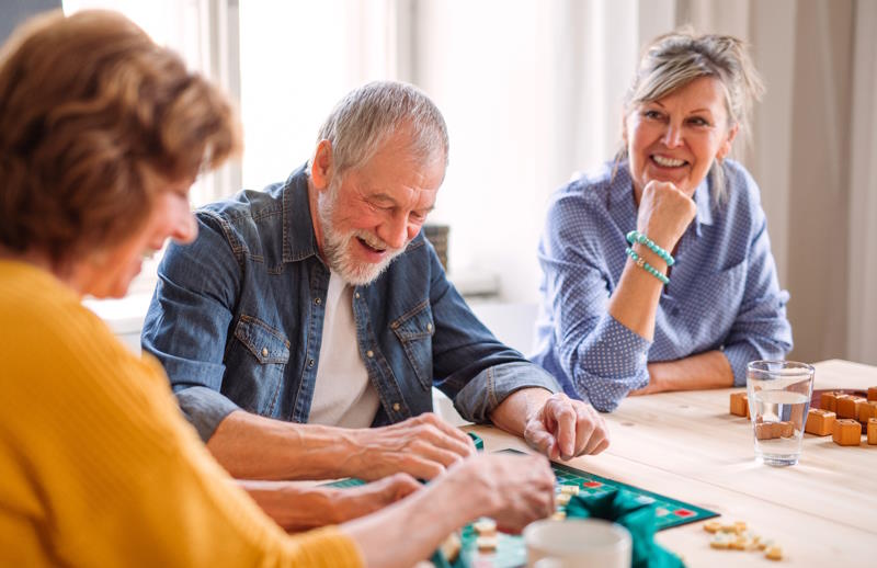 Animatrice regardant en souriant un couple de seniors profitant d'une animation à domicile