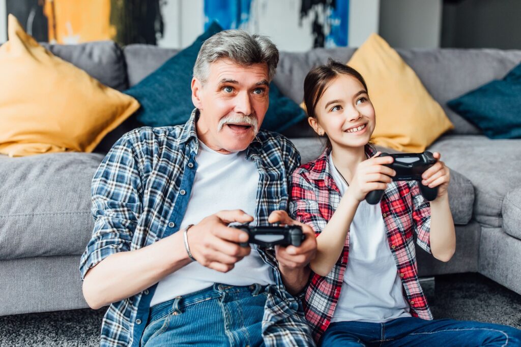 grand-père jouant aux jeux vidéos avec sa petite fille